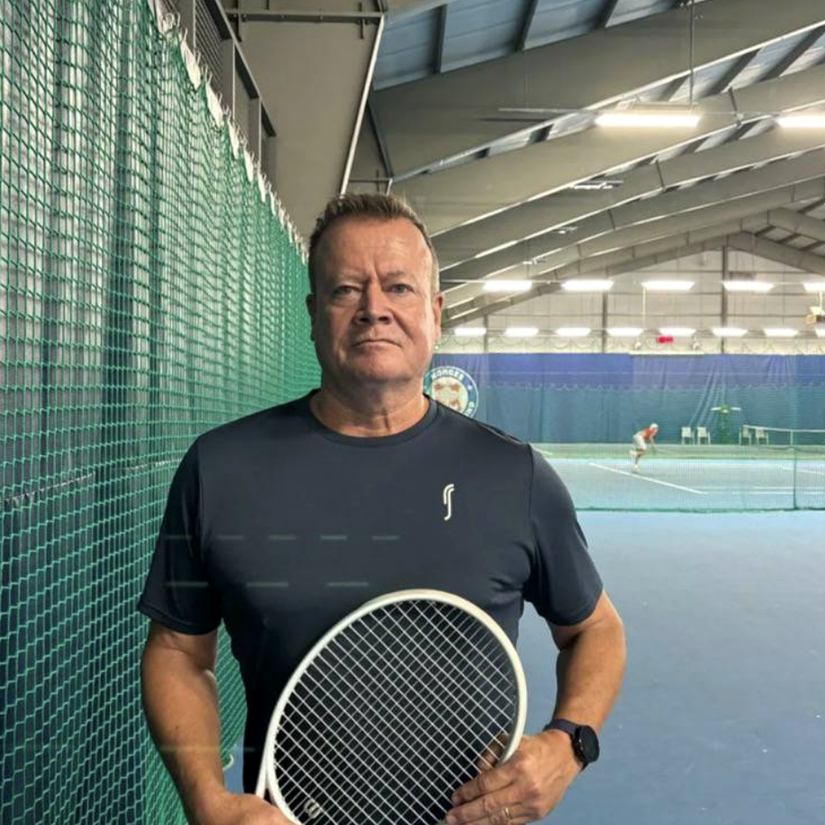 Pelle Fridell holding a tennis racket on an indoor tennis court.